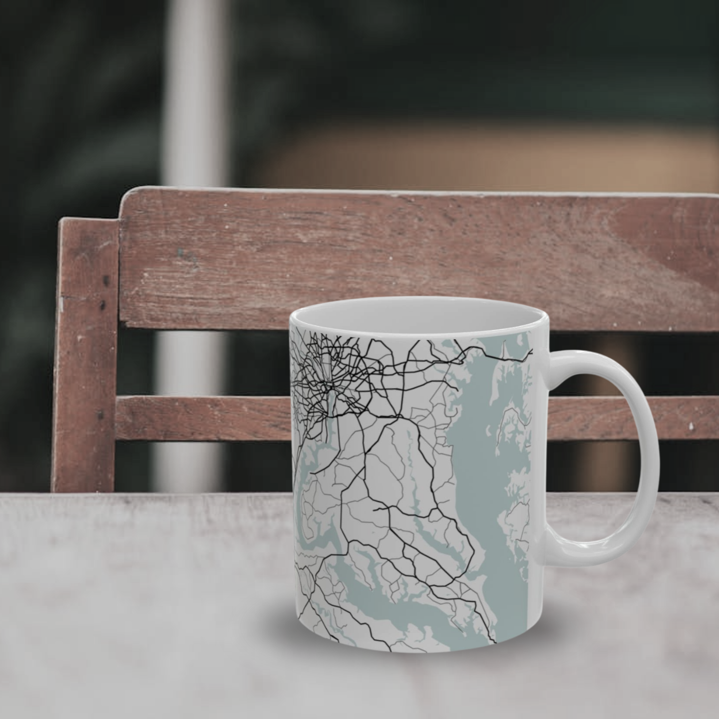 Atlas & Ink mug with a map design on a table with a blurred chair in the background