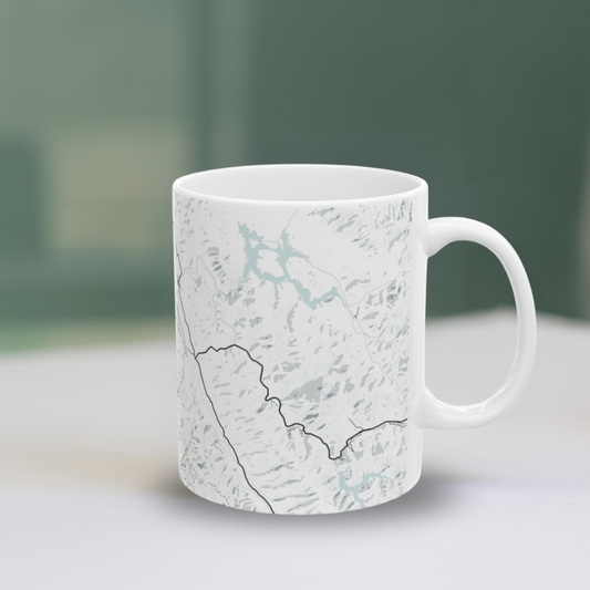 Atlas & Ink mug with a map design on a light surface with a green blurred background