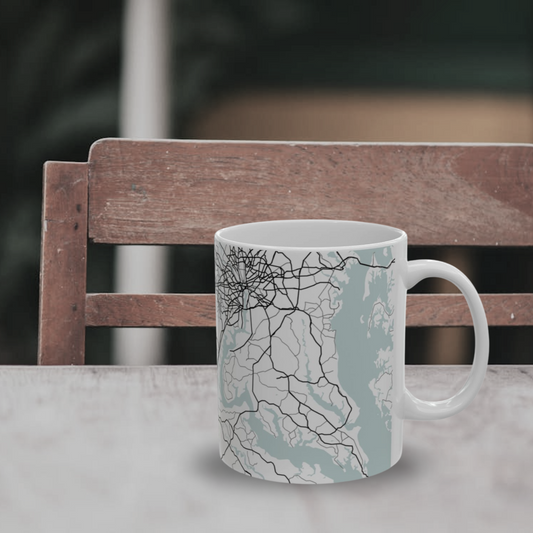 Atlas & Ink mug with a map design on a table with a blurred chair in the background